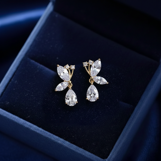 Butterfly-shaped earrings with clear stones on a dark blue velvet surface