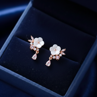 Floral earrings with rose gold and clear gemstones on a dark blue velvet surface