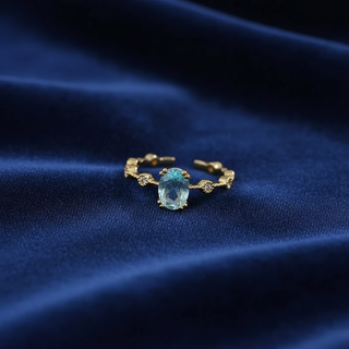 Gold ring with a blue gemstone on a dark blue fabric background