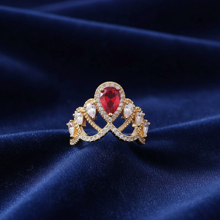 Gold ring with a red gemstone on a dark blue fabric background