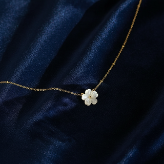 Gold necklace with a white flower pendant on a dark blue fabric background