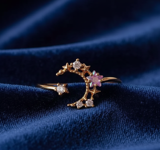 Gold ring with star and moon design on a blue fabric background