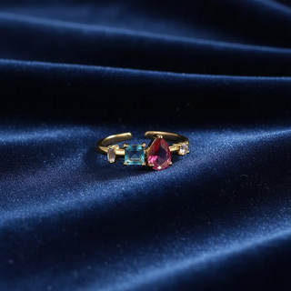 Gold ring with colorful gemstones on a dark blue fabric background