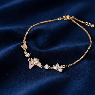 Gold bracelet with floral and leaf designs on a blue fabric background