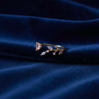 Delicate gold ring with pink gemstones on a blue fabric background